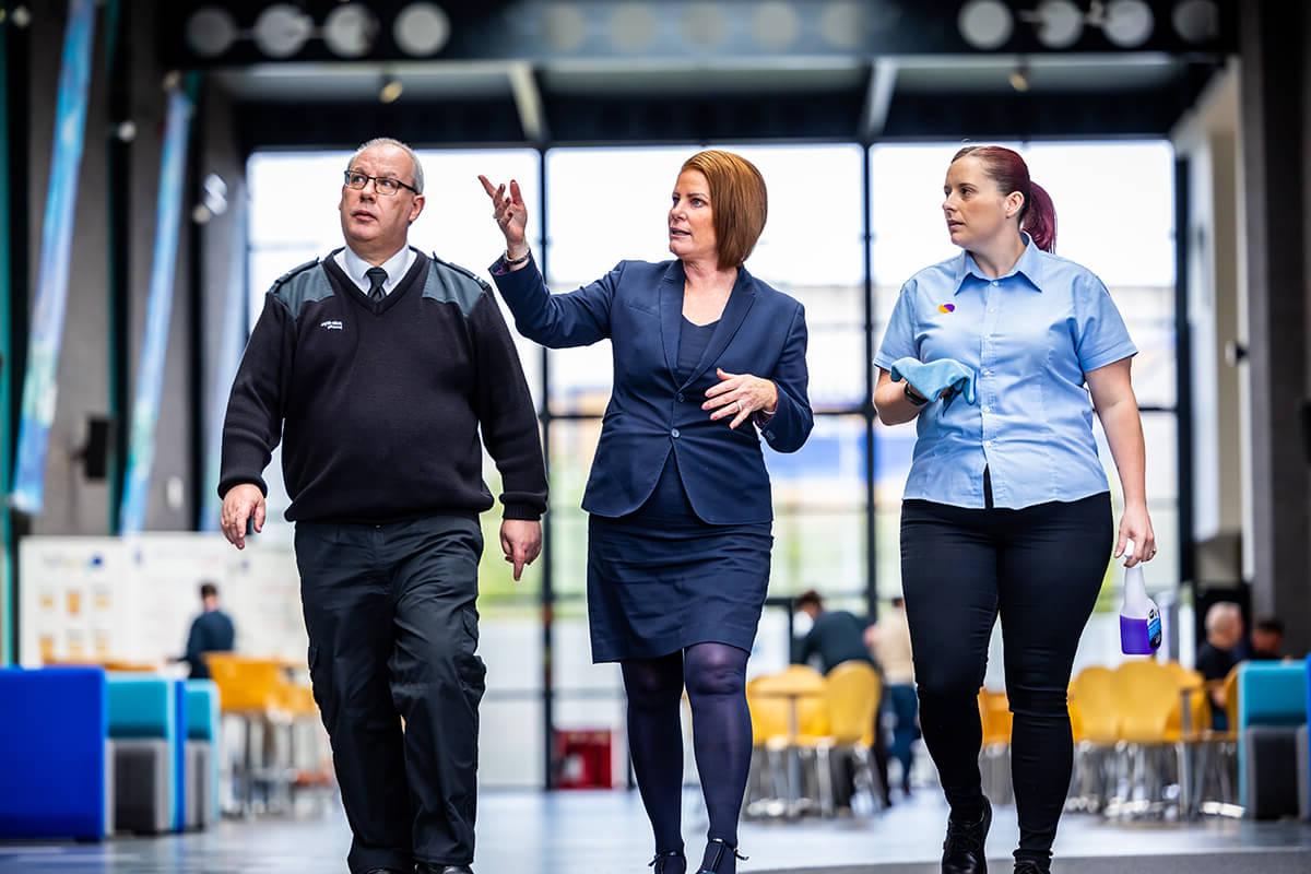 Three Mitie colleagues (front of house, cleaner and security guard) walking together in a reception area