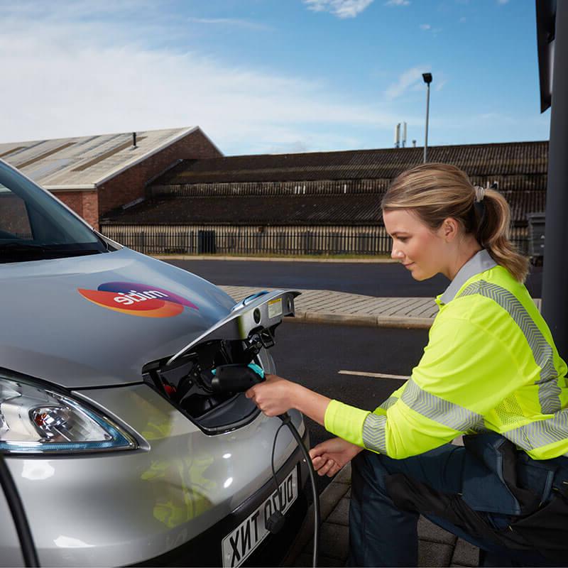 A Mitie employee in high vis plugging in a electric van to charge